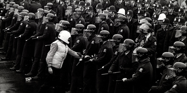 A protester places an olive branch onto the truncheon during protests at the All Blacks test against South Africa. File Photo / NZ Herald