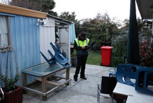 A security guard on duty in the backyard of a house where the body of a newborn girl was discovered. Photo / Mark Mitchell