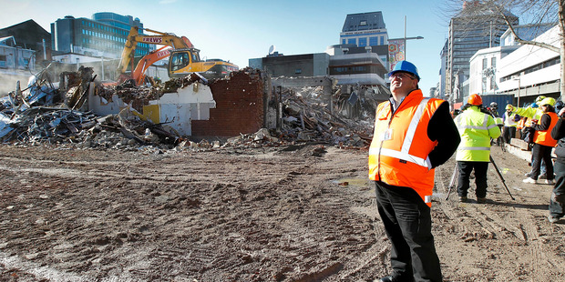 Earthquake Recovery Minister Gerry Brownlee watches demolition work on earthquake damaged buildings in Cashel Mall in Christchurch. Photo / Martin Hunter