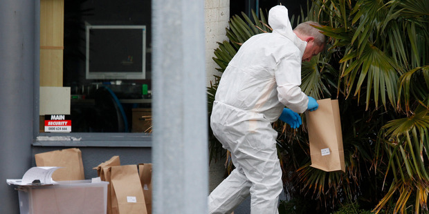 A police officer searches for clues at Kapiti Lights complex, Paraparaumu. Photo / Mark Mitchell