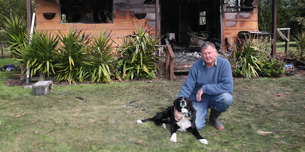 Chris Gubb with his dog Jack in front of the house that was gutted by fire in Te Puna. Photo / Bay of Plenty Times