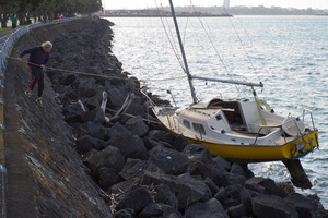 Paddy Evans looks over his stranded yacht at Tamaki Drive after its moorings broke in heavy seas on Saturday night. Photo / Greg Bowker