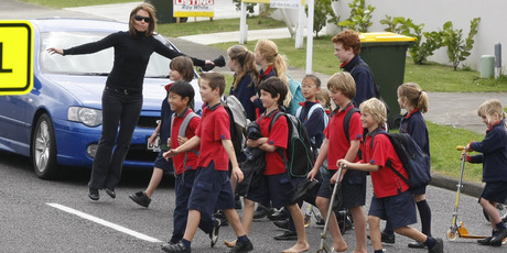 Children from the Bucklands Beach Primary School cross the road under the close guidance of a teacher. Photo / APN