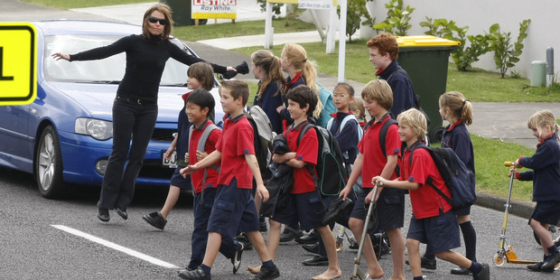 Children from the Bucklands Beach Primary School cross the road under the close guidance of a teacher. Photo / APN