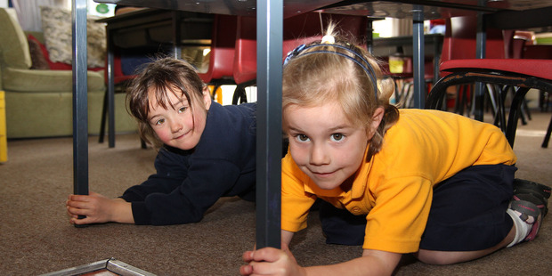 At Spreydon School's new entrant class, Mihana Hof (5) and Chloe Palmer (6) practice the Drop, Cover and Hold drill. Photo / NZ Herald
