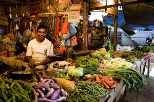 A vendor sells fruit and vegetables at his market stand Photo / Babiche Martens