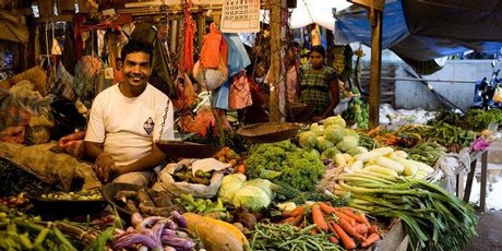 A vendor sells fruit and vegetables at his market stand Photo / Babiche Martens