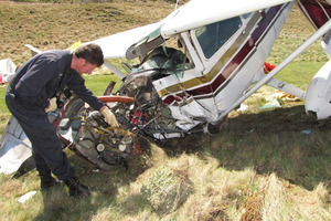 Civil Aviation Authority safety investigator Colin Grounsell examines the wreckage of the Cessna that crashed on the Arrowtown golf course just under a year ago. Photo / James Beech