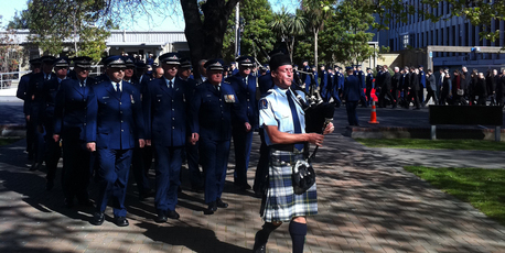 Hundreds of officers and civilian staff, led by a single piper, marched together. Photo / APNZ