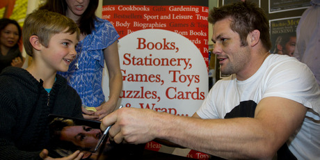 A smile and a chat as Richie McCaw signs his new book, The Open Side, for aspiring All Black Matthew Greenough, 8, in Auckland yesterday. Photo / Sarah Ivey