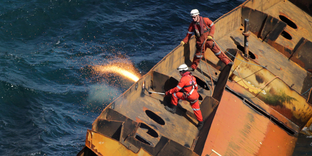 Salvors cut away parts of the wreck of the Rena. Photo / Alan Gibson
