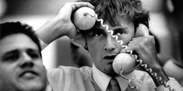 A sharemarket dealer has his hands full during hectic trading at the Auckland exchange in 1987. Photo / APN
