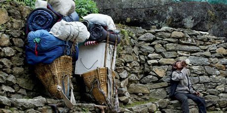 A Sherpa porter rests along side his heavy load on the Everest trail in the Solu Khumbu region, Nepal. Photo / Supplied