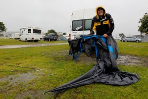 Brian Riley from Warkworth packs up his drenched tent to move to a cabin at the Kopua Holiday Park at Raglan. Photo / Christine Cornege