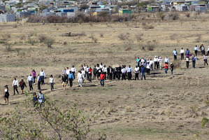 A large crowd follows retired judge Ian Farlam and his team as they inspect the area where the bodies of mine workers were found. Photo / AP