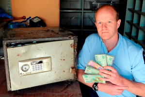 Sergeant Craig Dinnissen with the money and the safe found in the bush. The safe is believed to have been from a burglary two years ago. Photo / Linda Robertson