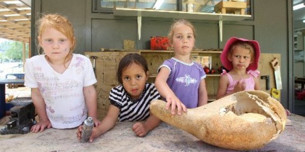 Amber Gleeson, Nevaeh-Lee Matiu,3, Isabella Troughton,4, and Sangreal Ekins, 3, of Maungaarangi Kindergarten with a gourd that was smashed by vandals. Photo / Joel Ford