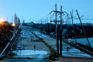 Downed power lines and a battered road is what superstorm Sandy left behind as people walk off the flooded Seaside Heights island. Photo / AP