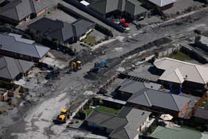Workers clean up the black gunk which is caused by the liquefaction in Christchurch. Photo / Brett Phibbs