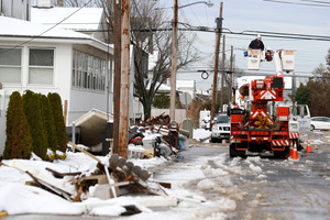Utility workers check the power lines as snow covered debris from Superstorm Sandy lay on the side of a street following a nor'easter storm in New Jersey. Photo / AP