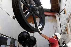 Atlas Cranes worker Jimmy Crowther steadies a section of the a 100 plus-year-old air compressor from Dive HQ. Photo / John Stone