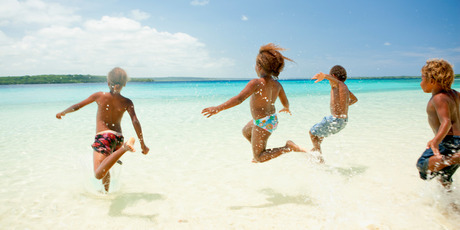 Kids cavort in the shallows of Champagne Beach. Photo / Supplied