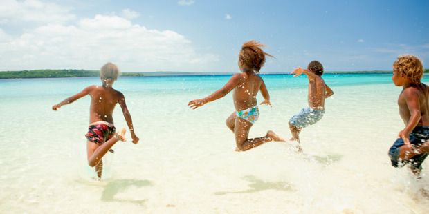 Kids cavort in the shallows of Champagne Beach. Photo / Supplied