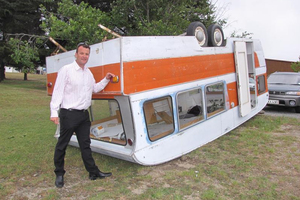 Glen Christiansen, of Cromwell, inspects his family's caravan which was lifted into the air and flipped on to its roof by a whirlwind on Friday evening. Photo / Lucy Ibbotson