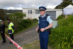 Police watch over a Tawa house where a woman's body was found. Photo / Mark Mitchell