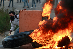 A Palestinian man hides during a protest against Israel's operations in Gaza Strip, outside Ofer, an Israeli military prison near the West Bank city of Ramallah. Photo / AP