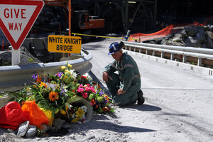 A miner laying down flowers at the White Knight Bridge near the entrance to the Pike River mine. Photo / Ross Setford