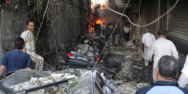 Syrian citizens gather at an alley destroyed by two cars bombs, at Jaramana neighbourhood, in the suburb of Damascus. Photo / AP