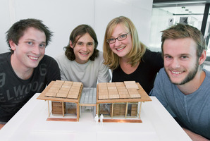 Nick Officer (left), Ben Jagersma, Anna Farrow and Eli Nuttall, with a model of the First Light energy-efficient home. Photo / Supplied