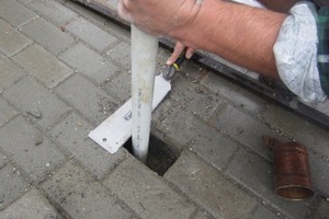Slide a piece of aluminium or stainless steel tube into the hole in the paver to act as a sleeve.