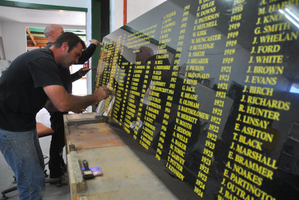 Greymouth Star Monumental masons Jamie Rhodes, front, and Mike Johnson gild one of the panels for the Greymouth miners' memorial with 23 carat gold. Photo / APN