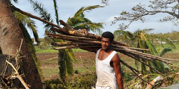 Cyclone Evan destroyed many homes in Nadi while in Lautoka a resident stocks up on newly created firewood. Photo / Fiji Ministry of Information