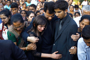 Husband Benedict Barboza, centre, holds his son Junal and daughter Lisha during the burial of Jacintha Saldanha. Photo / AP