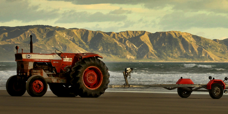 An old tractor and trailer await the return of a boat full of fishermen from an early morning trip off Waimarama Beach. Photo / Alan Gibson