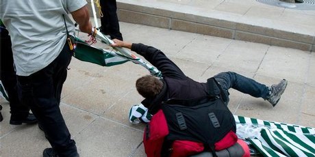 A protestor holds his ground as security staff remove Occupy Auckland from Aotea Square. Photo / Dean Purcell