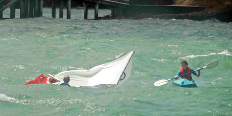 A kayaker goes to the aid of a sailor who capsized off Island Bay, North Shore yesterday. The Coastguard came to the rescue shortly after this picture was taken. Photo / Owen Blackburn