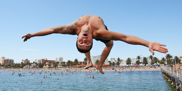 Jershon Witehira jumps into the water from a pier at St Kilda Beach in Melbourne. Forecasters predict the hottest, longest heat wave in Australia's history. Photo / Getty Images