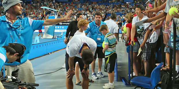 A corporate box facia gives way as spectators surge to get an autograph from Novak Djokovic. Photo / Getty Images
