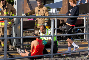 A woman is treated by a paramedic at the Morningside Drive rail crossing after she tried to help a disabled woman whose wheelchair became stuck. Photo / Brett Phibbs