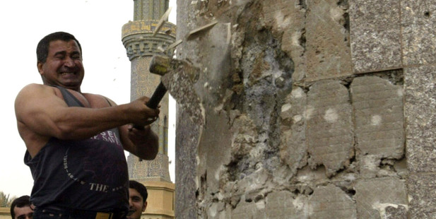 Kadom al-Jabouri swings a hammer at a statue of Saddam Hussein in downtown Bagdhad. Photo / AP