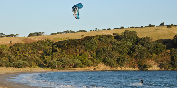 A kite-surfer zooms past at Te Haruhi Bay, Shakespear regional park. Photo / Liz Light