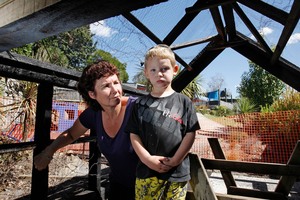 Head teacher Shelly Prisk with a very disappointed 3-year-old Dearne Fowler inside the burnt out whare. Photo / John Stone