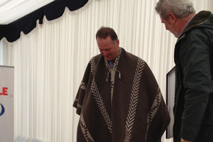 John Key received a poncho from farm manager Alberto Cussens. Photo / Claire Trevett