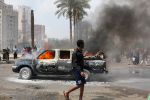 An Egyptian walks by a burning police vehicle in Tahrir Square. Photo / AP
