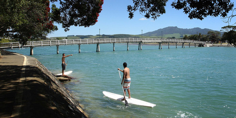 Paddleboarders make their way under the iconic Kopua footbridge that crosses Raglan harbour. Photo / Alan Gibson