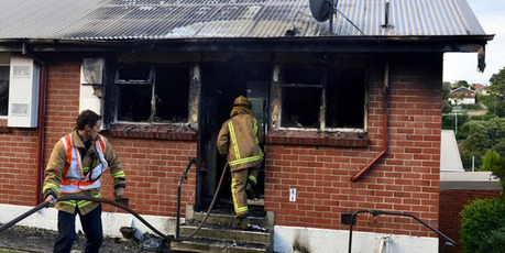 Firefighters begin dampening down hot spots following a house fire in Mornington. Photo / Peter McIntosh